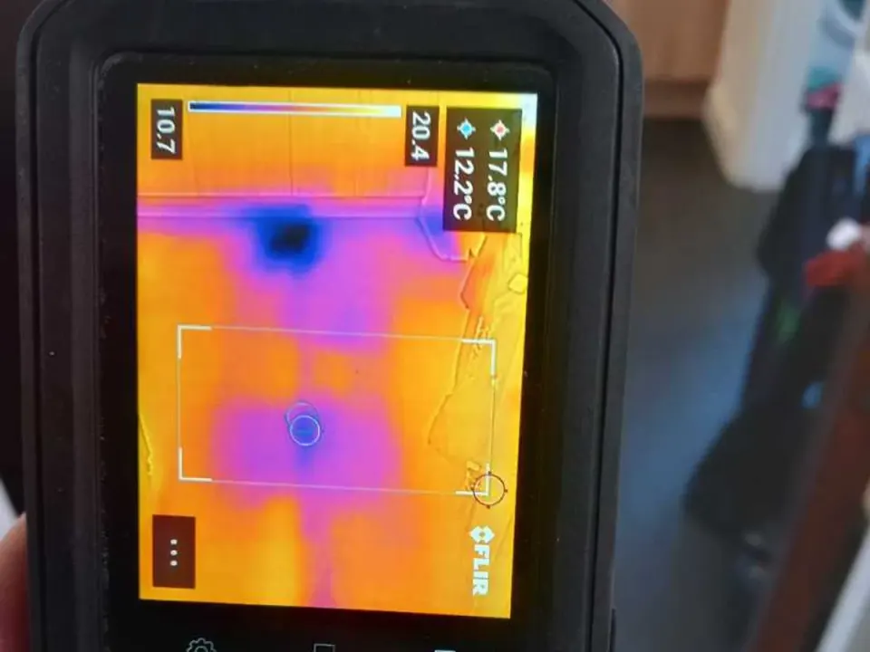 Thermal imaging camera screen showing cold anomaly in kitchen floor during leak detection