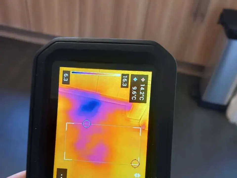 Thermal imaging camera screen showing cold pipe trace beneath kitchen floor during leak detection